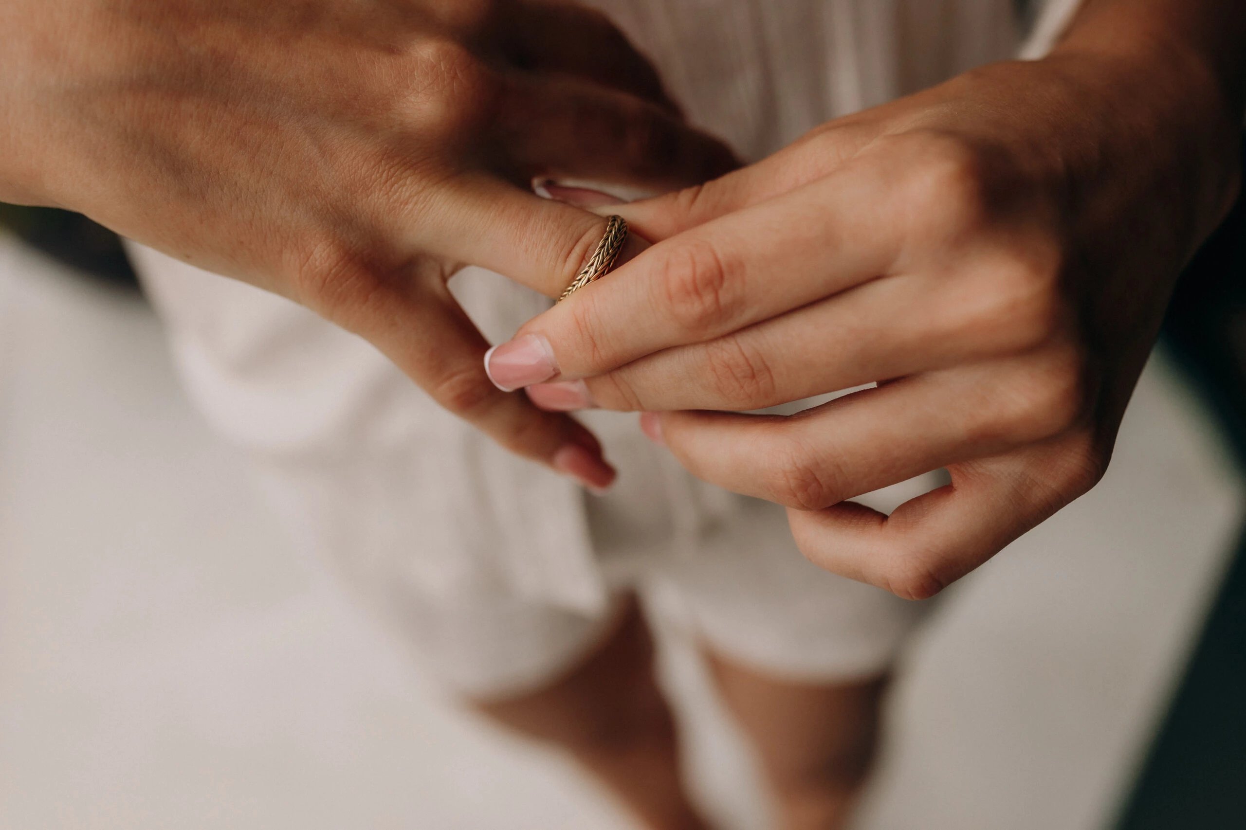 Person placing a braided gold ring on another's finger