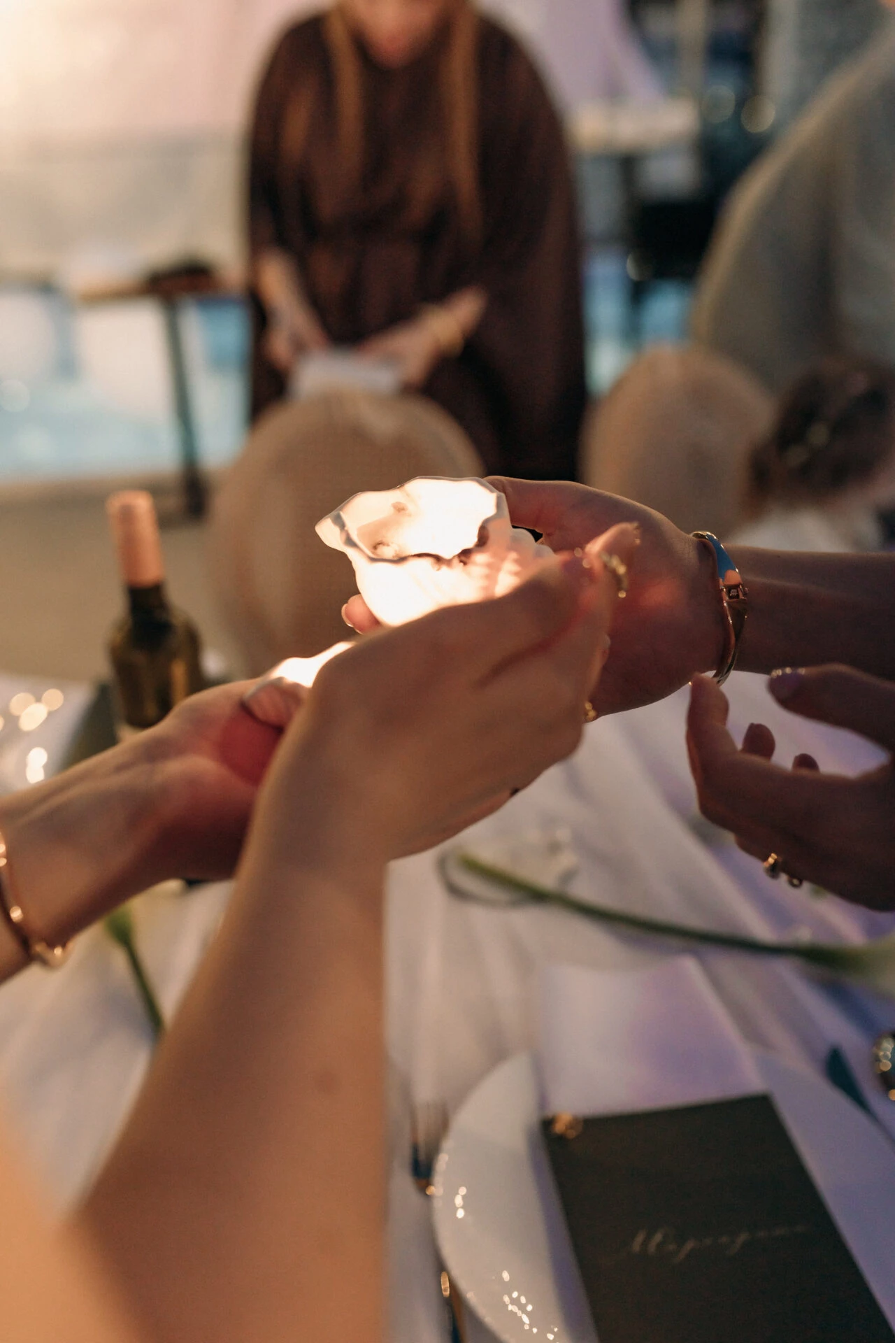 Hands holding a flaming oyster shell at dinner